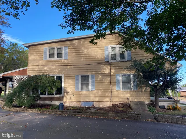 a front view of a house with a tree