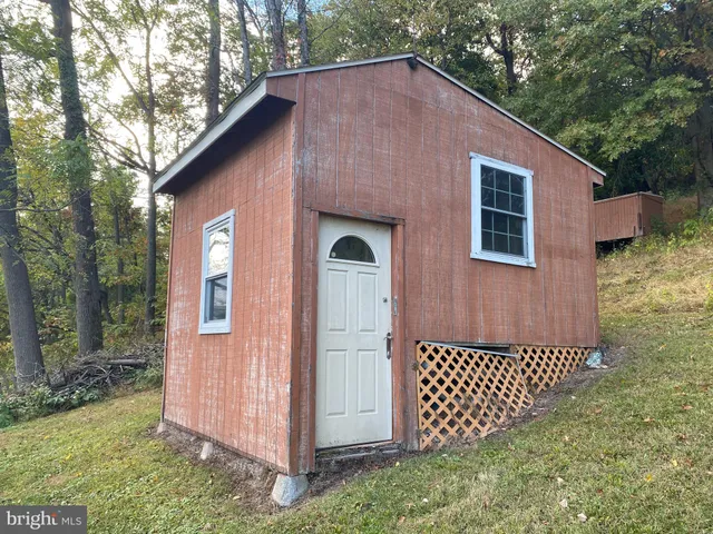 a view of a wooden house with a yard and seating space
