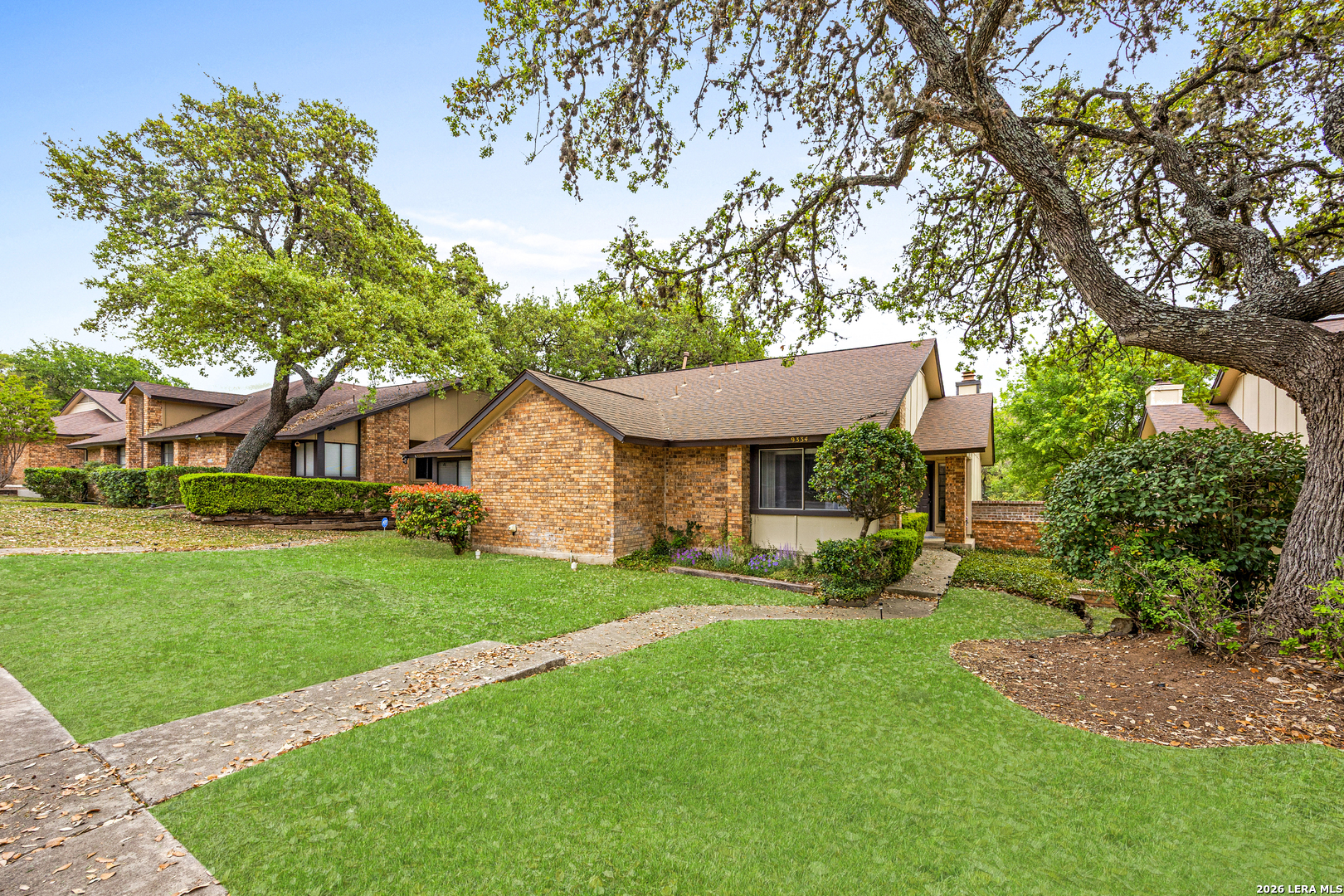 9334 Dover Ridge San Antonio, TX 78250 - Photo 3 of 42 a front view of a house with a garden and trees