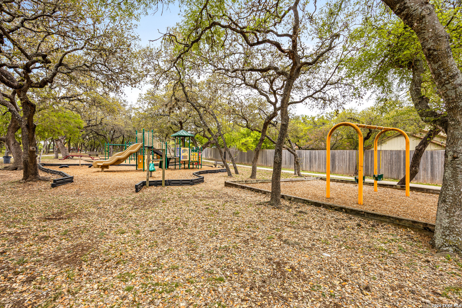 9334 Dover Ridge San Antonio, TX 78250 - Photo 39 of 42 a view of a park with swings and a large tree