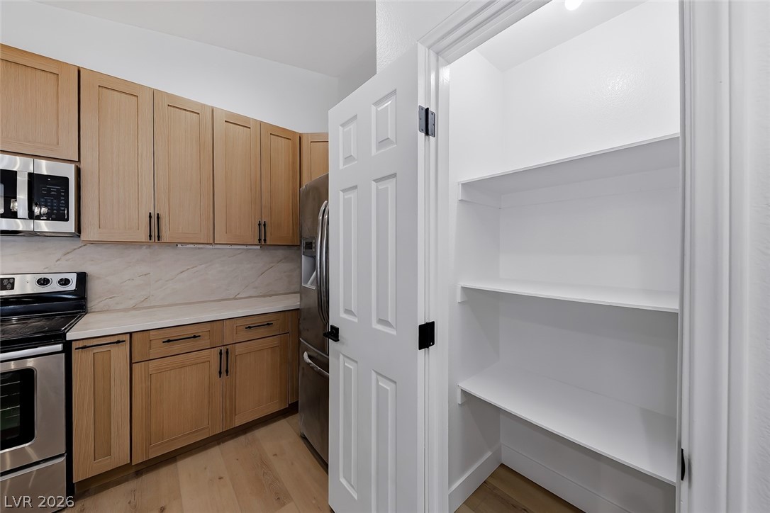 434 Crestway Road Henderson, NV 89015 - Photo 18 of 46 Kitchen with stainless steel appliances, light wood-style floors, tasteful backsplash, and wood finish cabinets