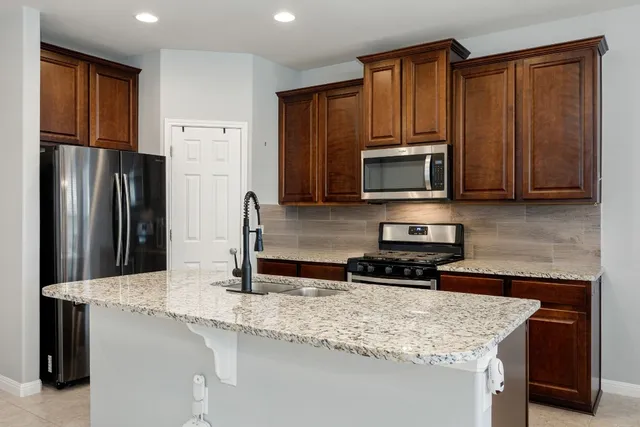 a kitchen with stainless steel appliances granite countertop a refrigerator microwave stove and sink