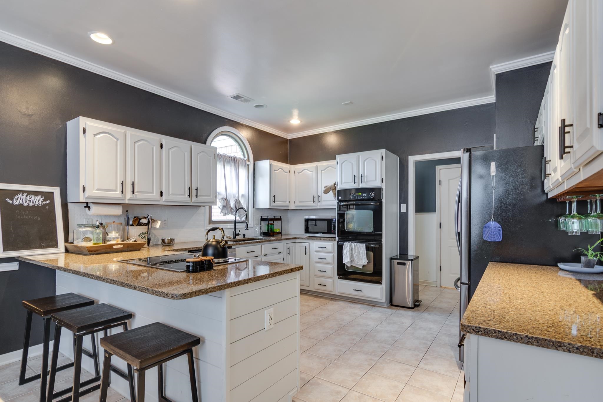 779 Early Earner Cove Collierville, TN 38017 - Photo 9 of 29 Kitchen featuring white cabinetry, light-toned countertops, a center island with built-in cooktop, double wall ovens, and tile flooring