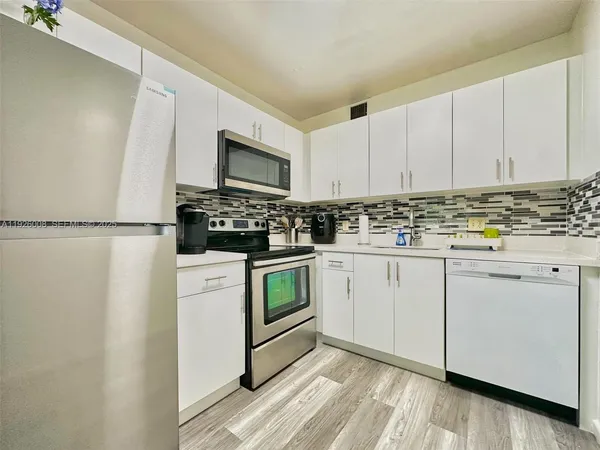 a kitchen with white cabinets white stainless steel appliances and sink