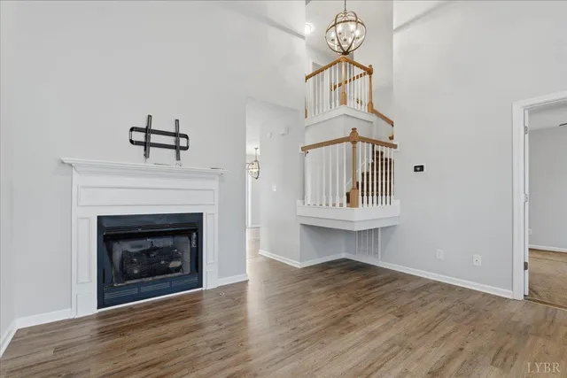 a view of an empty room with wooden floor fireplace and a window