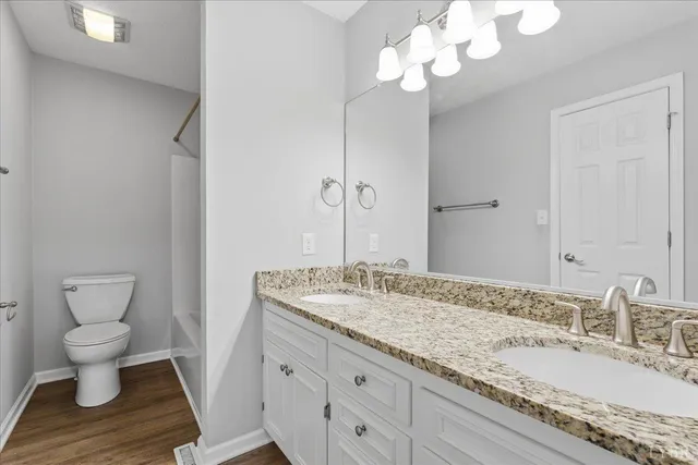 a bathroom with a granite countertop sink a toilet and a mirror