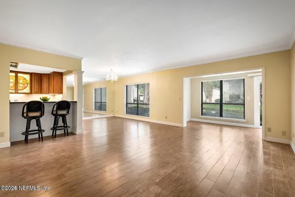 a view of an empty room with window and wooden floor