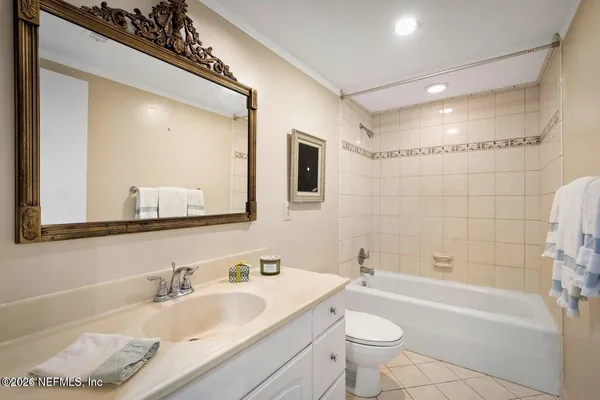 a bathroom with a granite countertop sink a toilet a mirror and bathtub