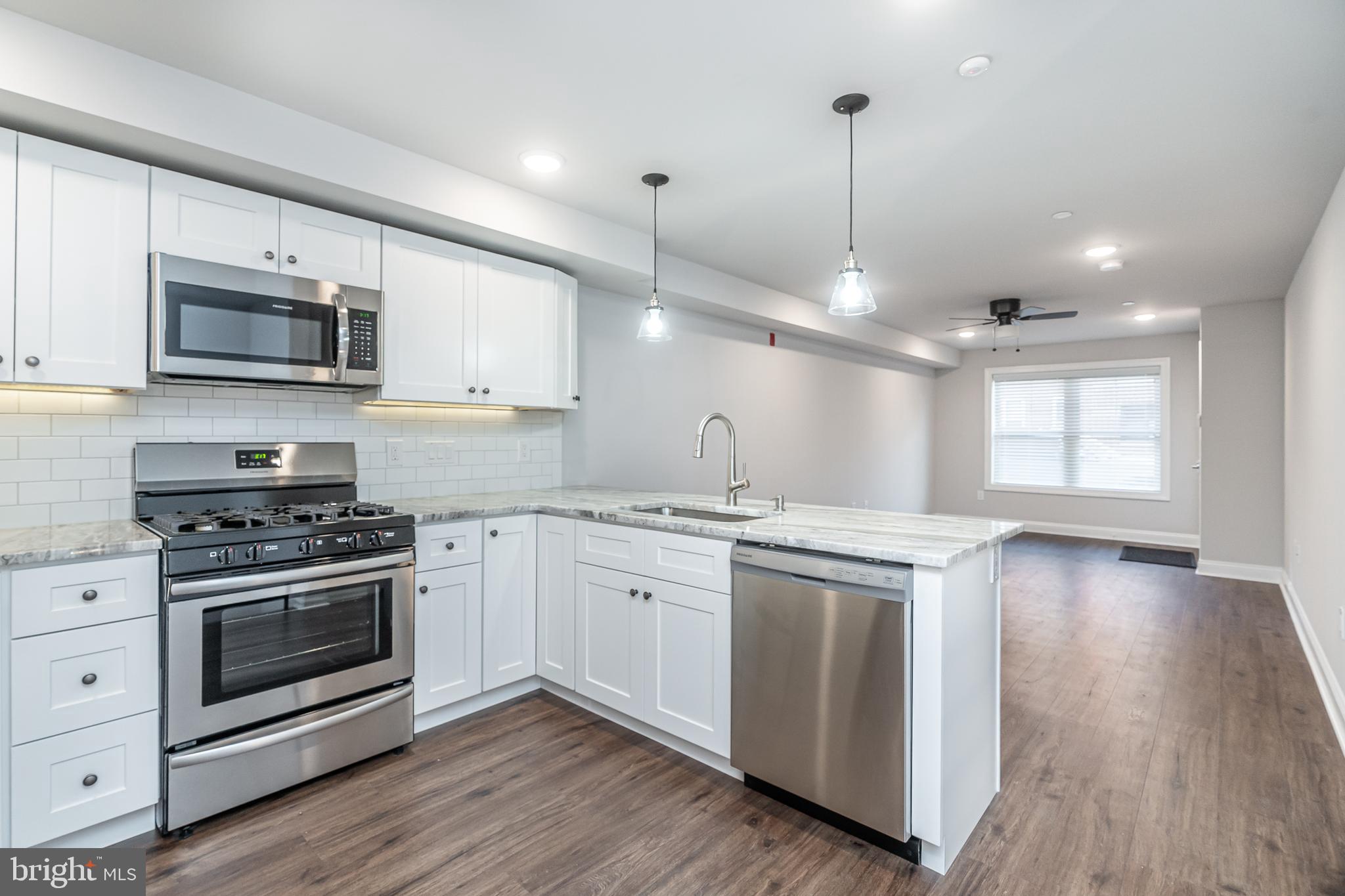 2202 Christian Street, Unit 1 Philadelphia, PA 19146 - Photo 17 of 27 a kitchen with stainless steel appliances granite countertop a stove a sink and a microwave