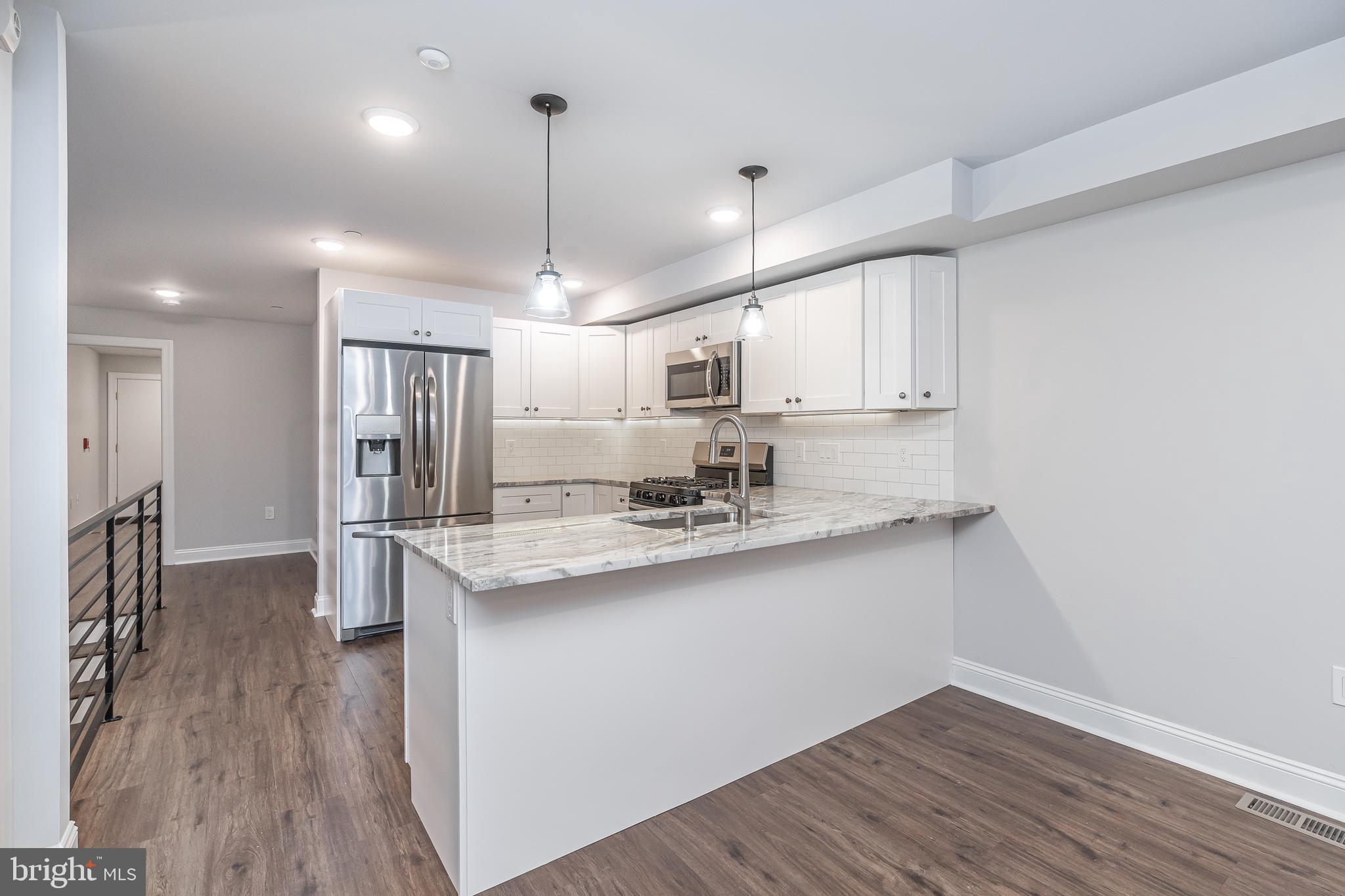 2202 Christian Street, Unit 1 Philadelphia, PA 19146 - Photo 6 of 27 a kitchen with stainless steel appliances granite countertop a sink a stove a refrigerator and wooden floor