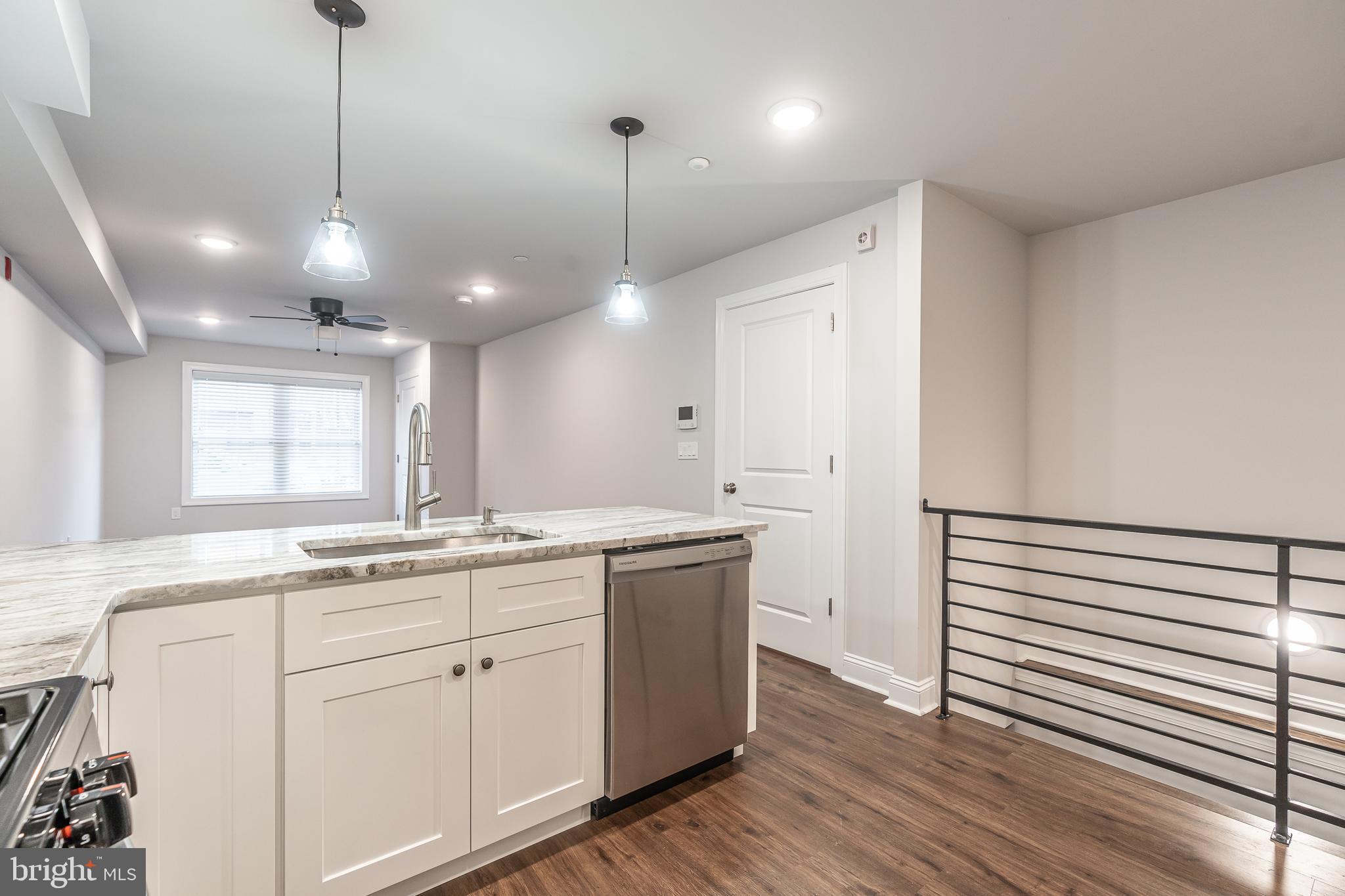 2202 Christian Street, Unit 1 Philadelphia, PA 19146 - Photo 10 of 27 a kitchen with a sink dishwasher and white cabinets with wooden floor
