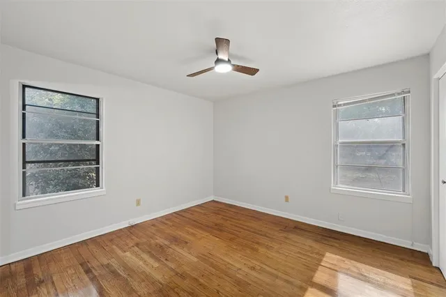 a view of empty room with wooden floor and fan