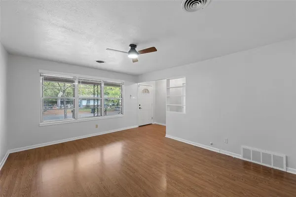 an empty room with wooden floor and windows