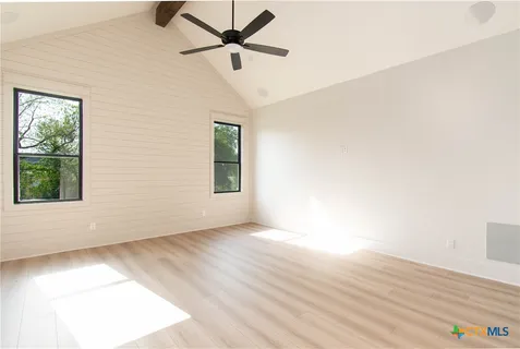 an empty room with wooden floor fan and windows