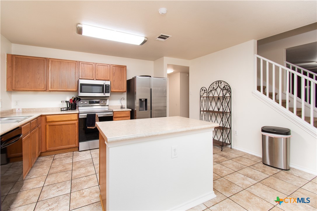 322 Fallen Leaf Lane Temple, TX 76502 - Photo 9 of 26 a kitchen with stainless steel appliances kitchen island granite countertop a refrigerator a stove top oven a sink a dining table and chairs