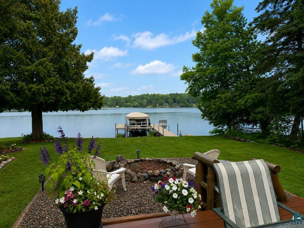 11058 South Brancel Road Solon Springs, WI 54873 - Photo 4 of 6 Waterfront property featuring a private dock with a boat lift, a manicured lawn, and mature trees