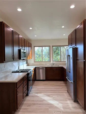 a large kitchen with a large counter top a sink stainless steel appliances and cabinets