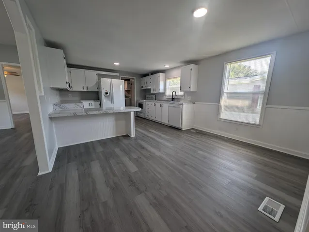 a kitchen with stainless steel appliances granite countertop a sink cabinets and wooden floor
