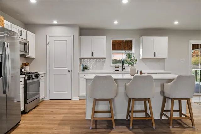 a kitchen with stainless steel appliances granite countertop a table chairs refrigerator and a sink