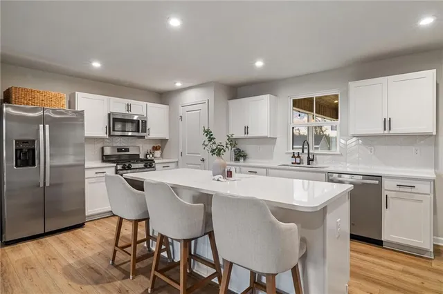 a kitchen with stainless steel appliances a dining table a microwave a sink and cabinets