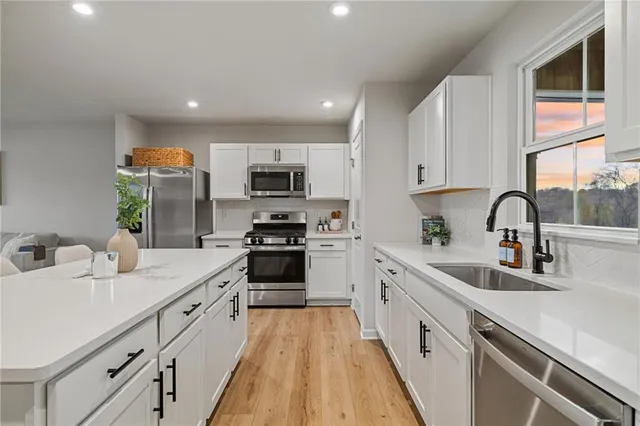 a kitchen with kitchen island granite countertop a sink a counter top space stainless steel appliances and cabinets