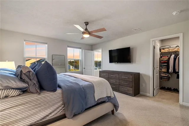 a spacious bedroom with a large bed a flat tv screen and dresser