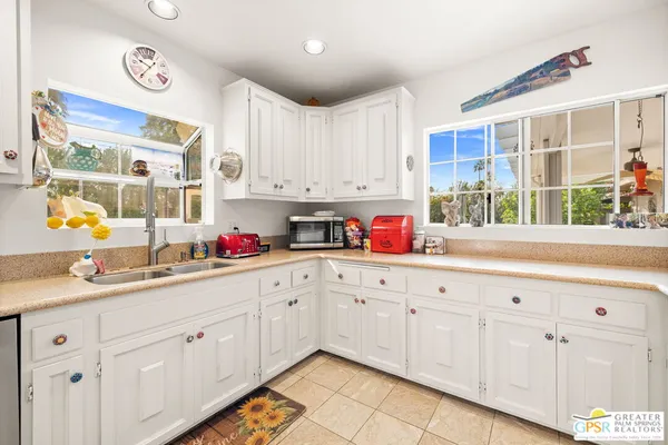 a kitchen with granite countertop white cabinets white appliances a sink and dishwasher
