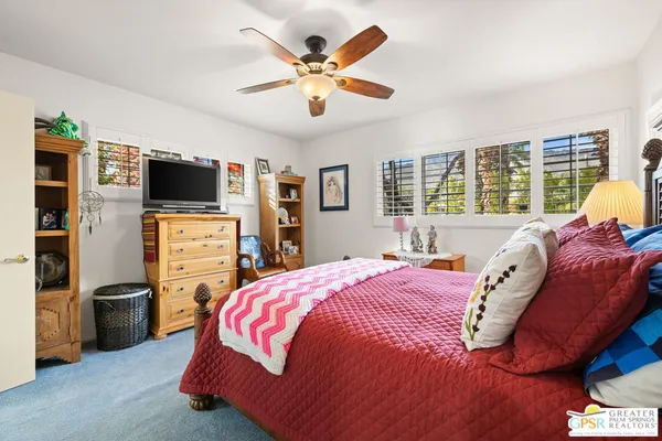a bedroom with a bed flat screen tv and a large window