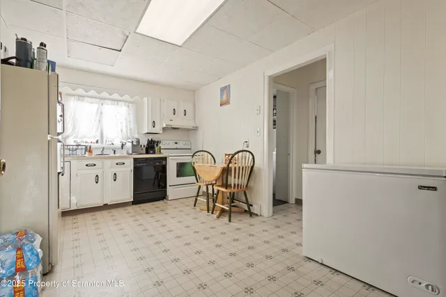 a kitchen with stainless steel appliances a refrigerator a sink a stove and white cabinets