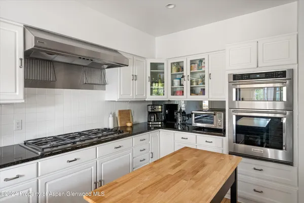 a kitchen with granite countertop a stove a sink and a refrigerator