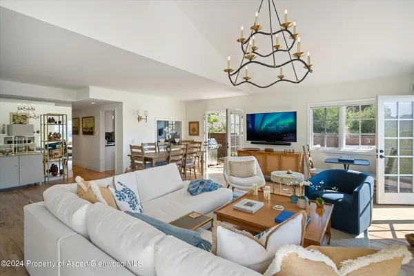 a living room with furniture a flat screen tv and floor to ceiling window