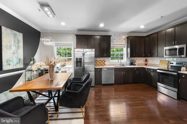 a kitchen with kitchen island a stove a sink a refrigerator a dining table and chairs