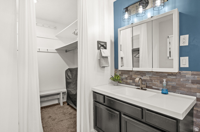 9750 Indian Ridge Drive Sandy, UT 84092 - Photo 34 of 40 Bathroom featuring vanity, carpet, and tasteful backsplash
