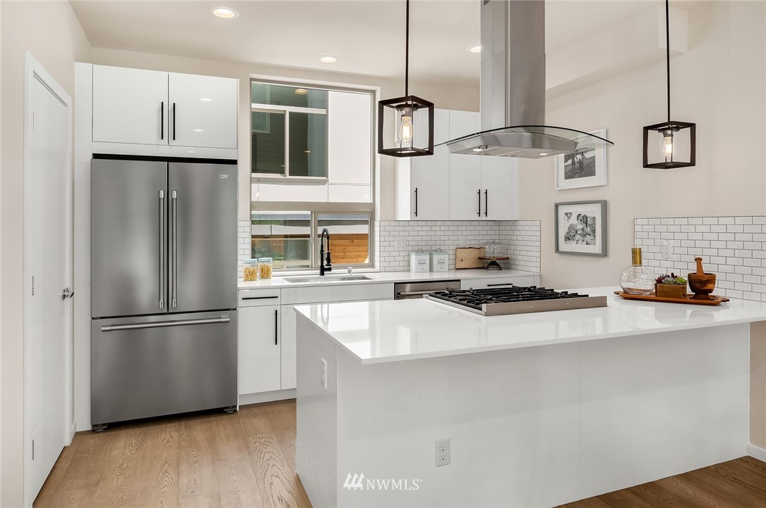 8370 Loyal Way Northwest, Unit B Seattle, WA 98117 - Photo 4 of 19 a kitchen with stainless steel appliances granite countertop a refrigerator a stove and a sink with wooden floors