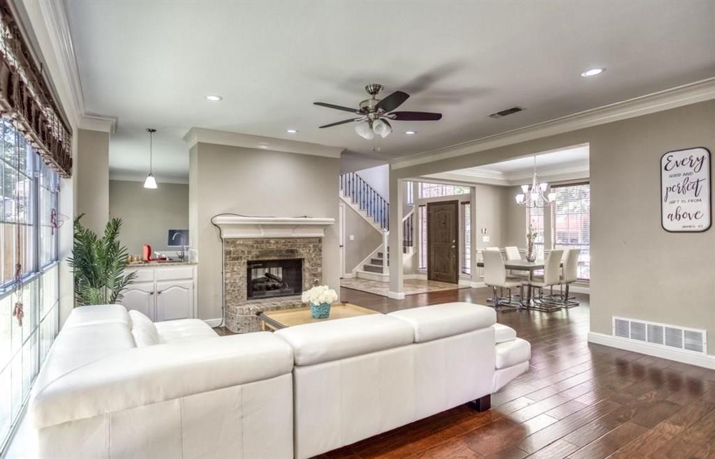 5421 North Briar Ridge Circle McKinney, TX 75072 - Photo 4 of 27 Living area featuring crown molding, dark wood-style flooring, a glass covered fireplace, ceiling fan, and stairs