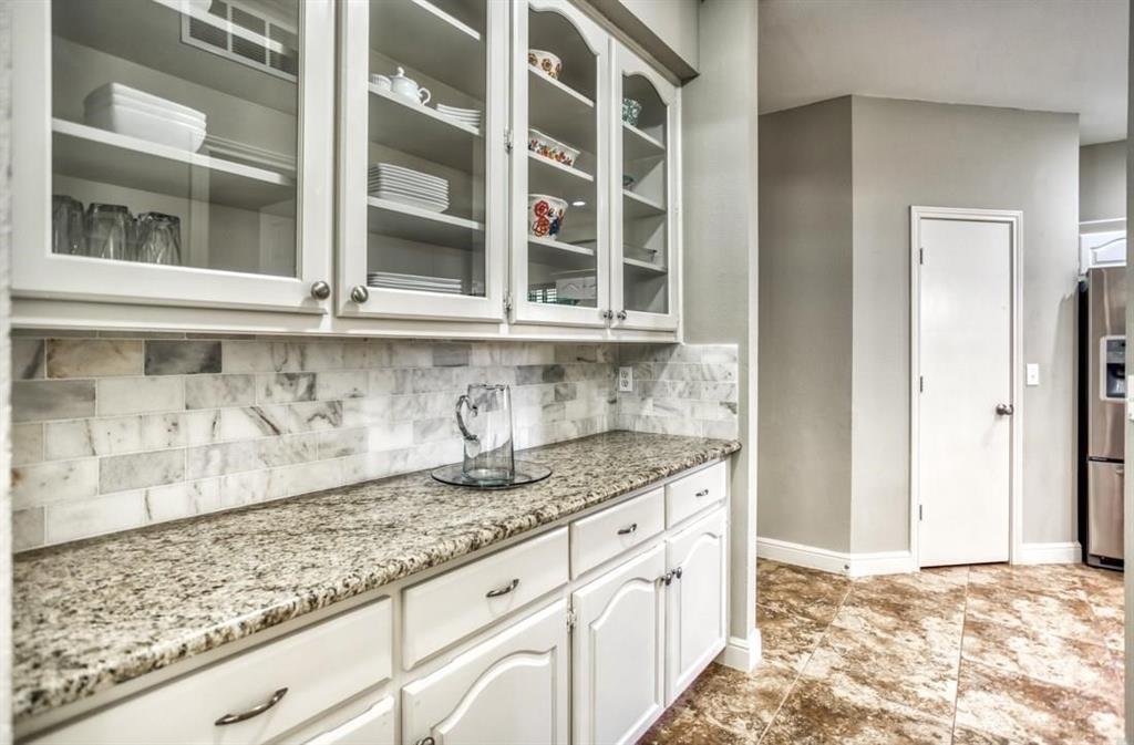 5421 North Briar Ridge Circle McKinney, TX 75072 - Photo 7 of 27 Bar area featuring light stone countertops, white cabinetry, decorative backsplash, stainless steel fridge, and glass insert cabinets