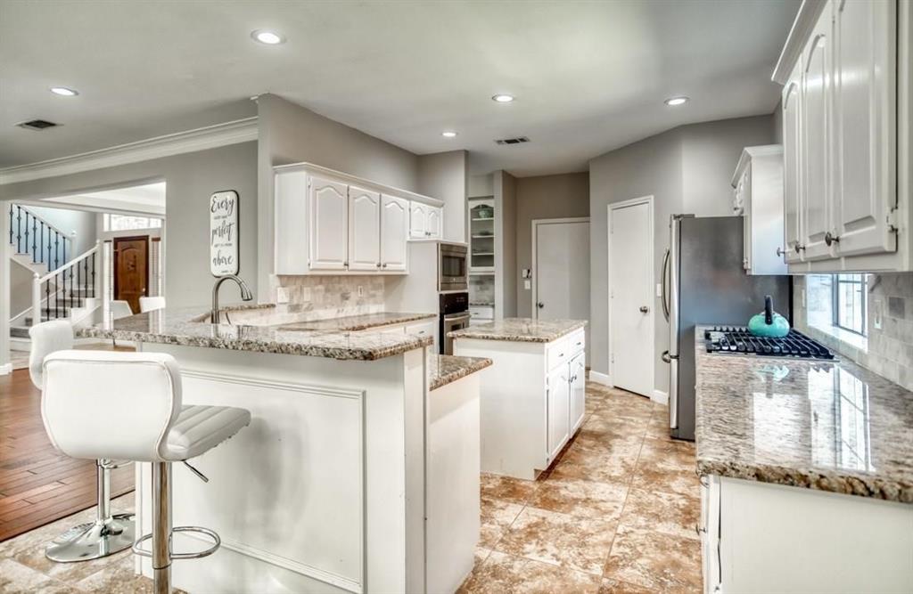 5421 North Briar Ridge Circle McKinney, TX 75072 - Photo 8 of 27 Kitchen featuring a kitchen island, backsplash, a kitchen breakfast bar, white cabinets, and recessed lighting