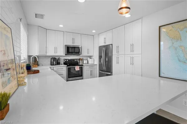 a kitchen with stainless steel appliances granite countertop white cabinets sink and a refrigerator