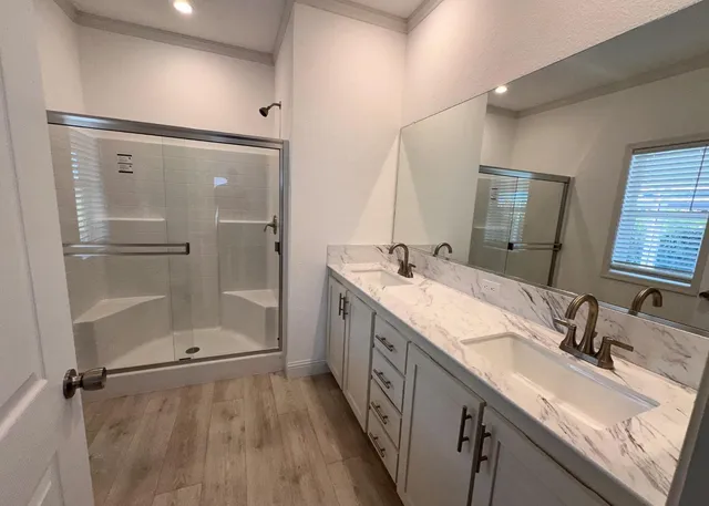 a bathroom with a double vanity sink mirror and shower