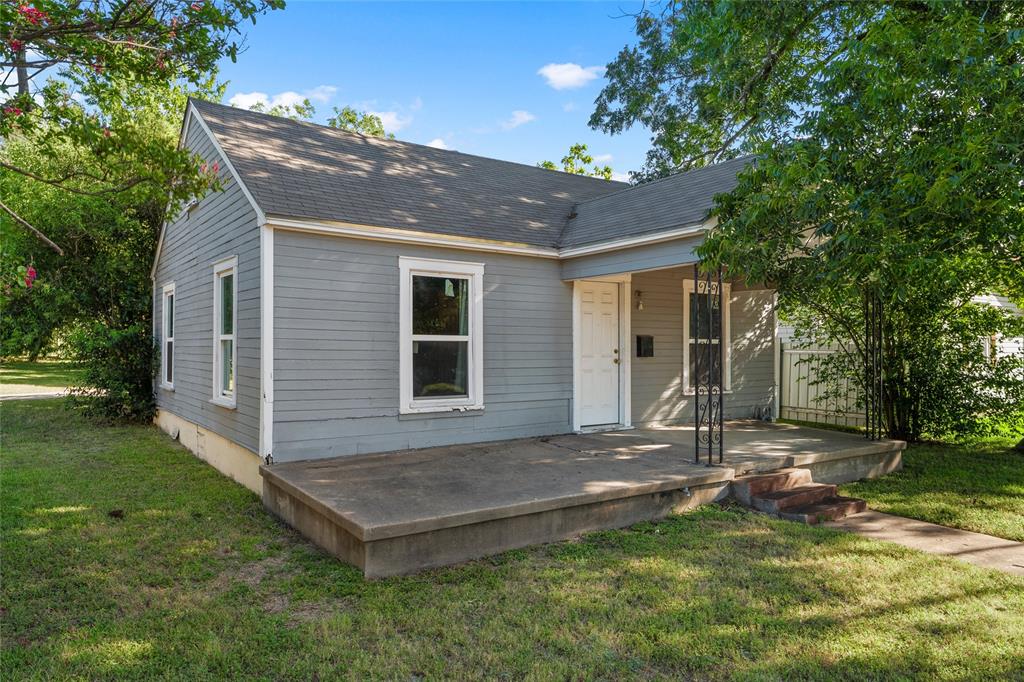 2225 Mitchell Avenue Waco, TX 76708 - Photo 2 of 16 Gray siding residence featuring a concrete front porch, white entry door, and a gabled roofline