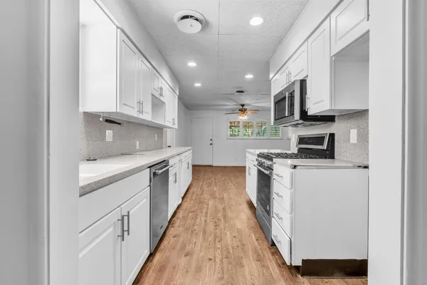 a kitchen with stainless steel appliances granite countertop lots of white cabinets a stove top oven a sink and dishwasher