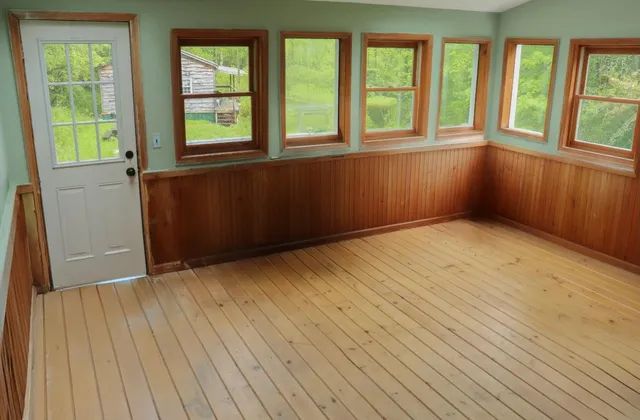 an empty room with wooden floor and windows