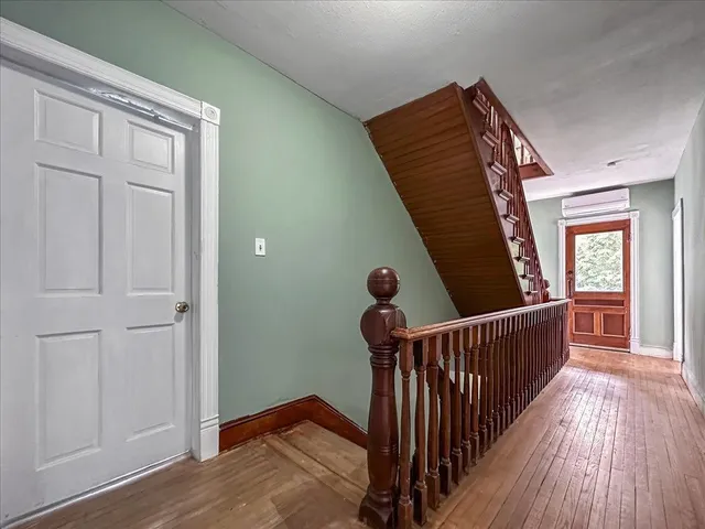 a view of a hallway with wooden floor and stairs
