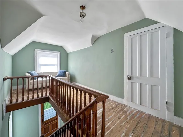a view of a hallway with wooden floor and stairs