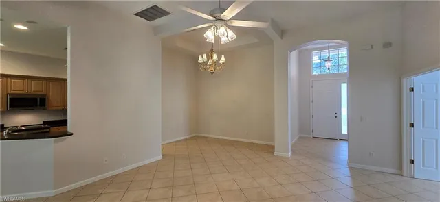 a view of an empty room with window and chandelier fan