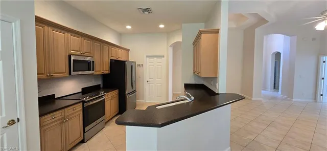 a kitchen with granite countertop a refrigerator and a stove top oven