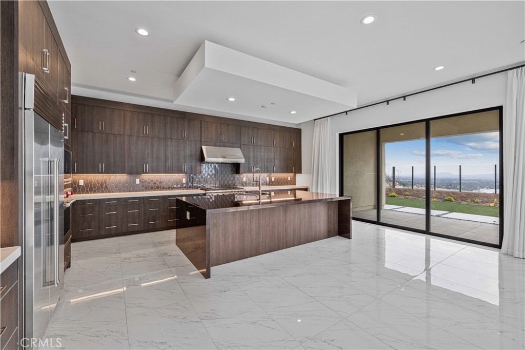 11752 Hillsborough Lane Porter Ranch, CA 91326 - Photo 10 of 45 a kitchen with stainless steel appliances kitchen island granite countertop a refrigerator a sink a stove with wooden cabinets