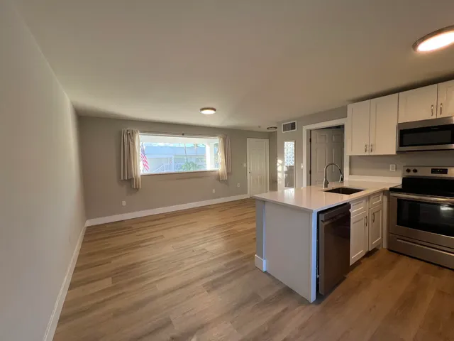 a kitchen with wooden cabinets a sink a stove a refrigerator with a dining table and chairs