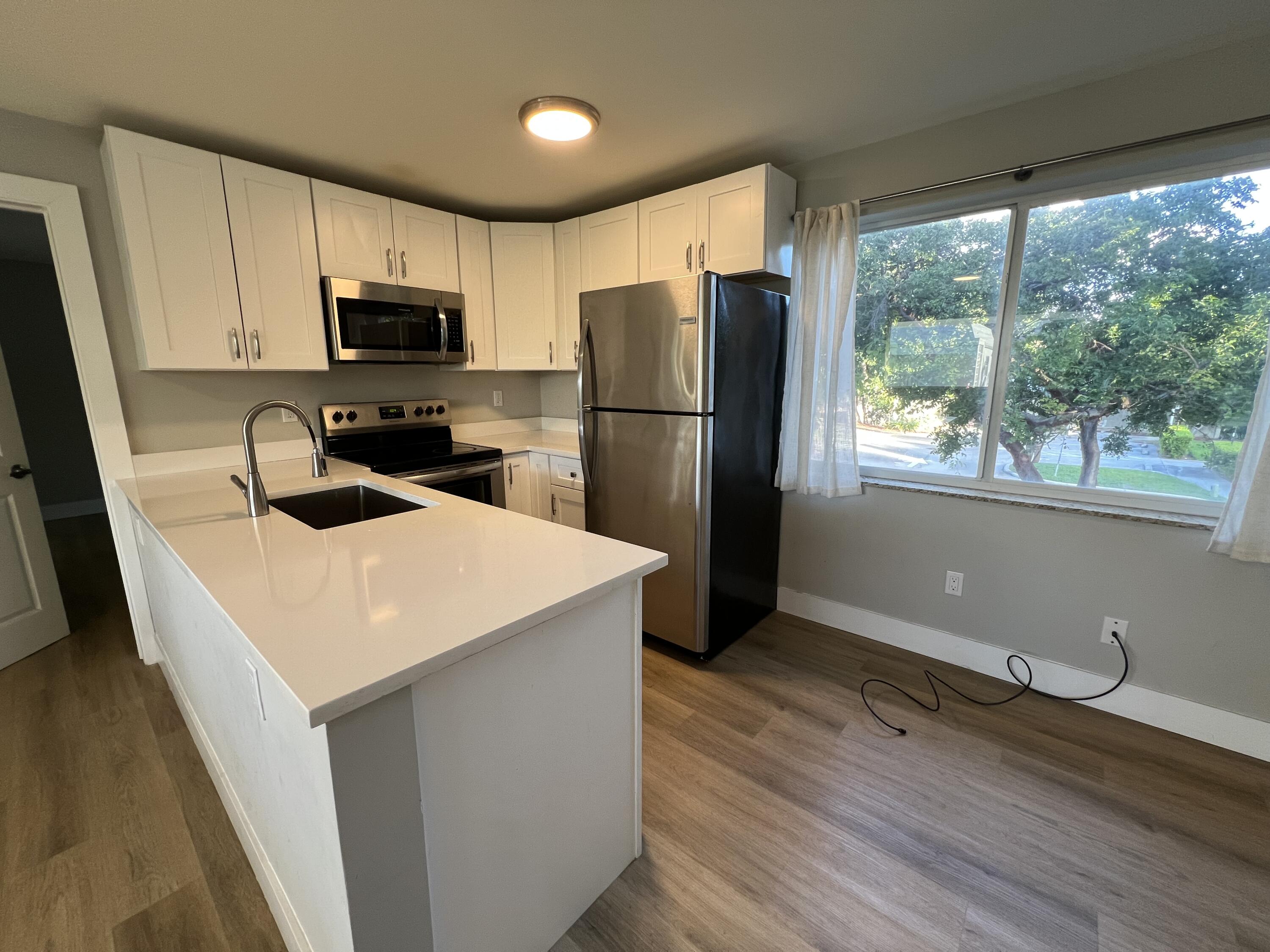 6600 North Ocean Boulevard, Unit 17 Ocean Ridge, FL 33435 - Photo 12 of 21 a kitchen with wooden cabinets a sink a stove a refrigerator with a dining table and chairs