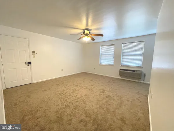 an empty room with chandelier fan and windows
